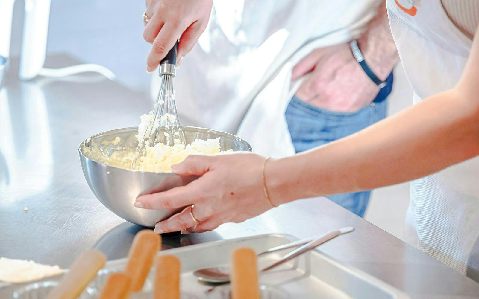 Hands whisking ingredients in a bowl during a small group cooking class in Florence.