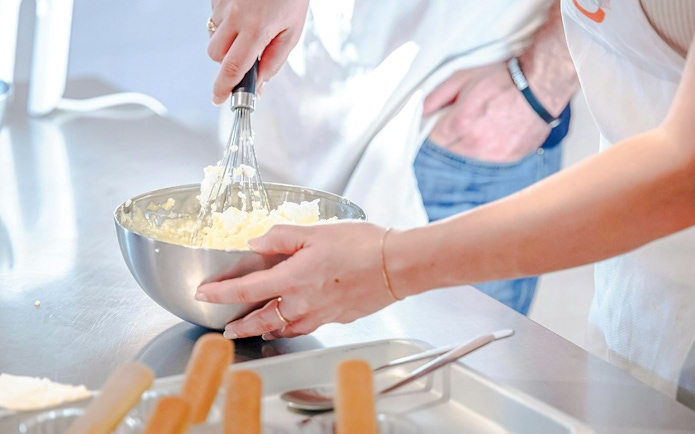 Hands whisking ingredients in a bowl during a small group cooking class in Florence.
