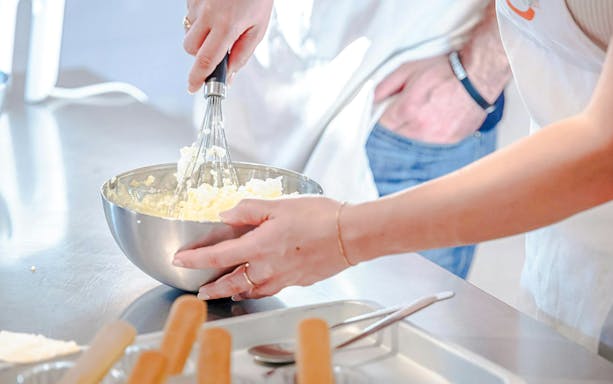 Hands whisking ingredients in a bowl during a small group cooking class in Florence.