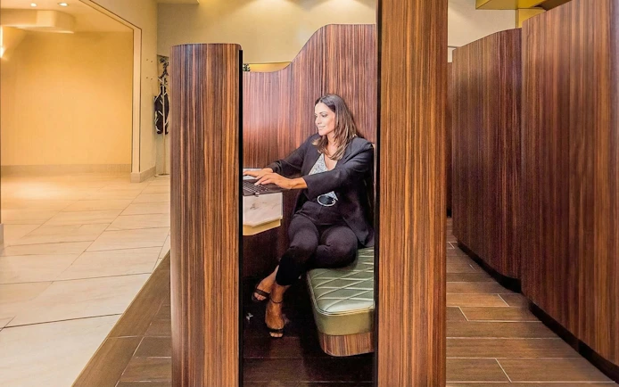 Person working on a laptop in a private booth at Mera VIP Lounge, Cancun Airport.