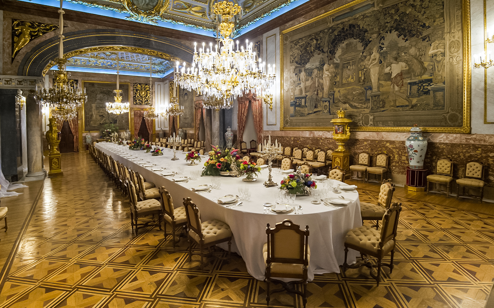 Dining hall with chandeliers and long table inside Royal Palace of Madrid.
