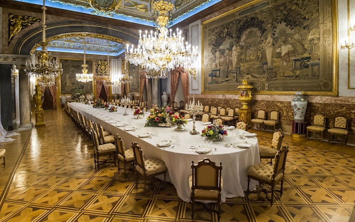Dining hall with chandeliers and long table inside Royal Palace of Madrid.