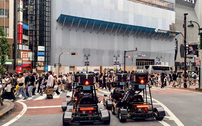 Go-karts driving through a busy intersection in Tokyo during a street kart experience.