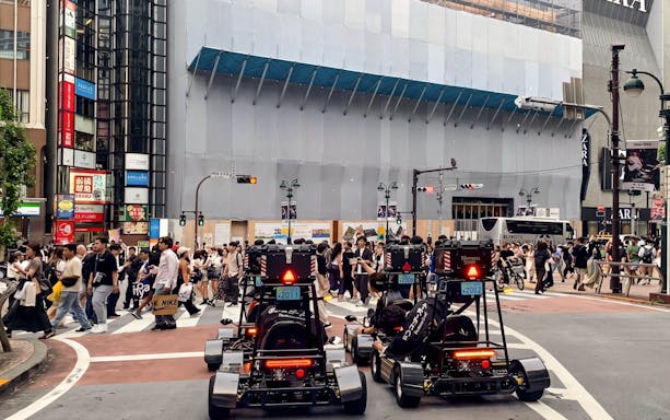 Go-karts driving through a busy intersection in Tokyo during a street kart experience.