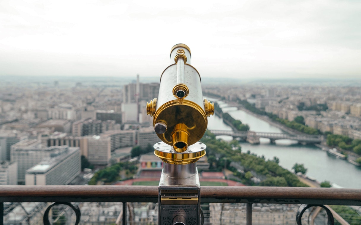 Telescope view from Eiffel Tower's second floor overlooking Paris and Seine River.