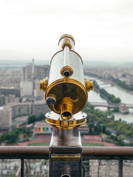 Telescope view from Eiffel Tower's second floor overlooking Paris and Seine River.