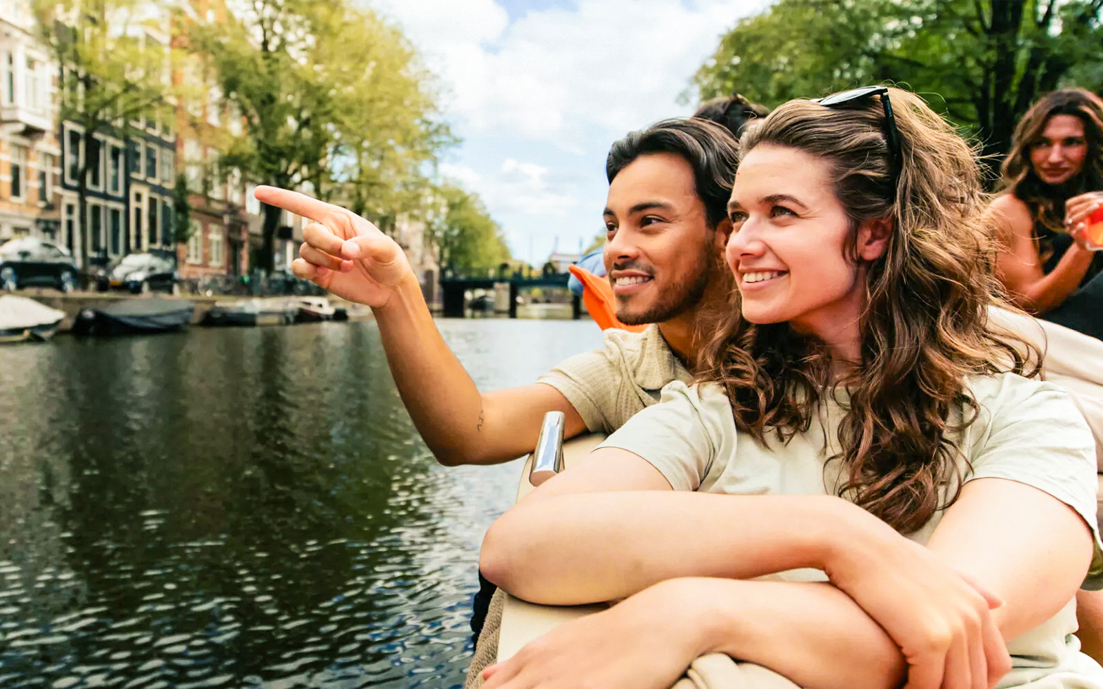 Amsterdam canal cruise with passengers enjoying drinks on a luxury open boat.