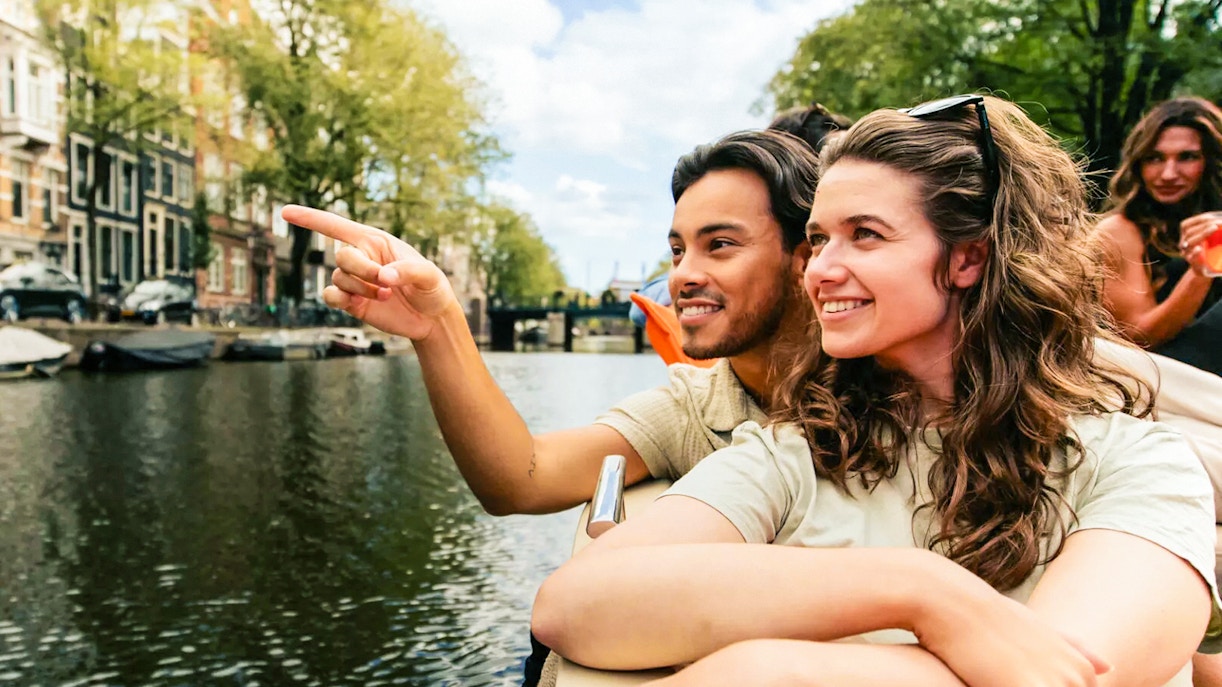 Amsterdam canal cruise with passengers enjoying drinks on a luxury open boat.