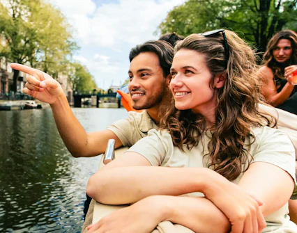Couple enjoying Amsterdam canal views on a luxury open boat cruise.