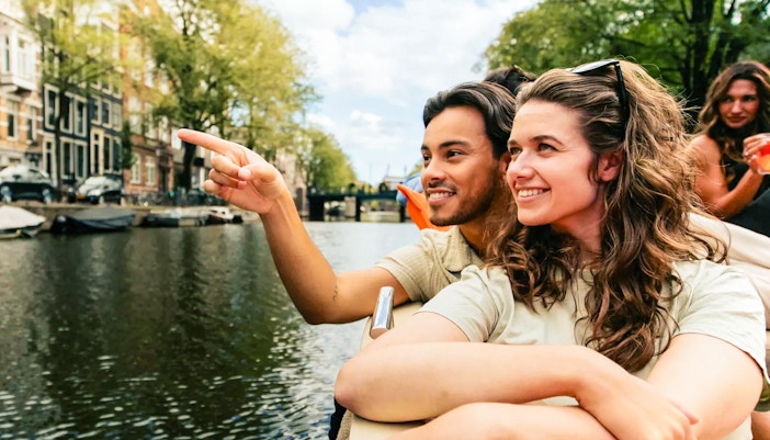 Amsterdam canal cruise with passengers enjoying drinks on a luxury open boat.