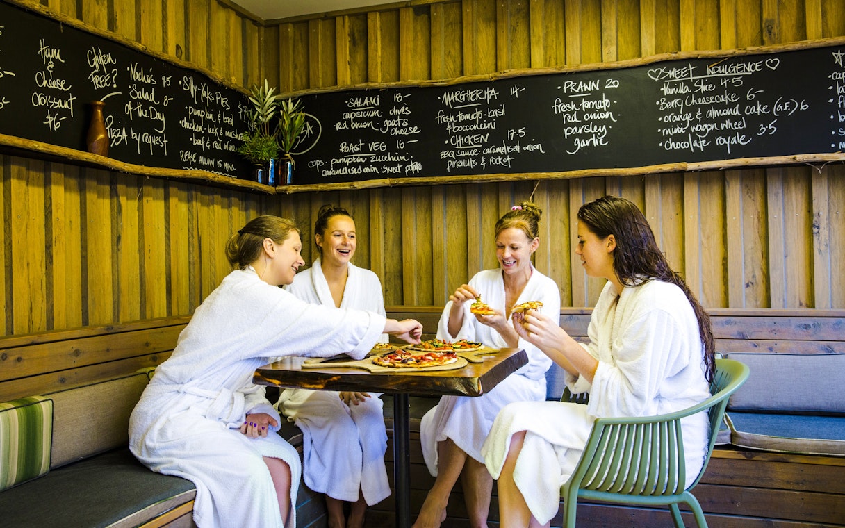 Guests in robes enjoying pizza at Peninsula Hot Springs café.