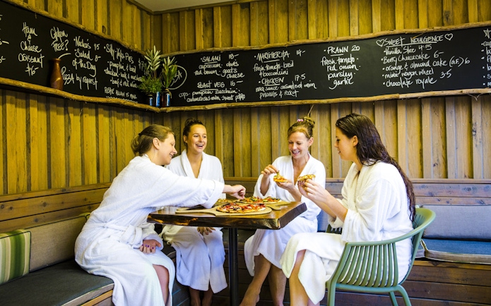 Guests in robes enjoying pizza at Peninsula Hot Springs café.
