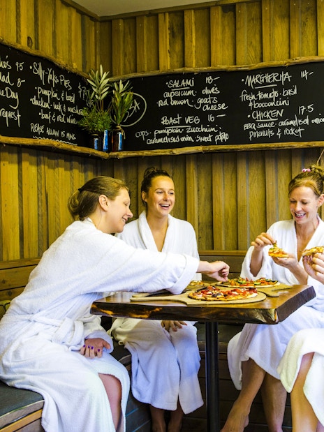 Guests in robes enjoying pizza at Peninsula Hot Springs café.