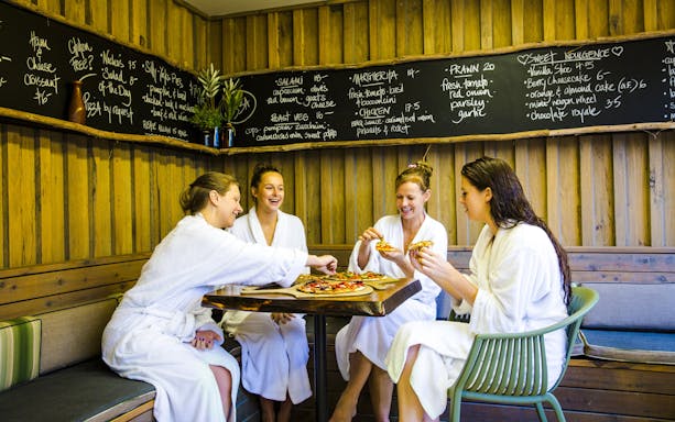 Guests in robes enjoying pizza at Peninsula Hot Springs café.