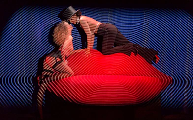 Performers on stage at Crazy Horse show in Paris, with vibrant lighting effects.