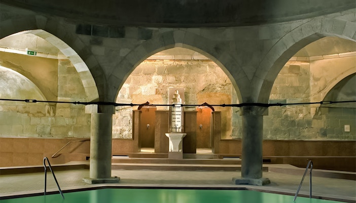 Rudas Thermal Spa interior at night with illuminated thermal pools and arched ceilings in Budapest, Hungary.