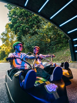 Friends riding luge carts into a tunnel on the Skyline Luge, Singapore.