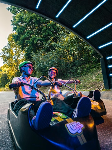 Friends riding luge carts into a tunnel on the Skyline Luge, Singapore.