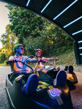 Friends riding luge carts into a tunnel on the Skyline Luge, Singapore.