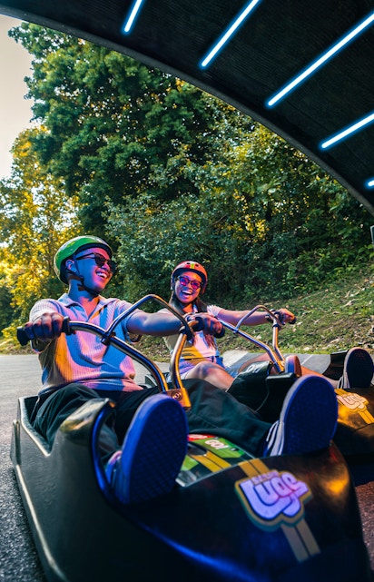 Friends riding luge carts into a tunnel on the Skyline Luge, Singapore.