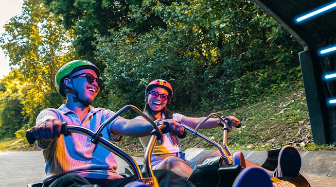 Friends riding luge carts into a tunnel on the Skyline Luge, Singapore.