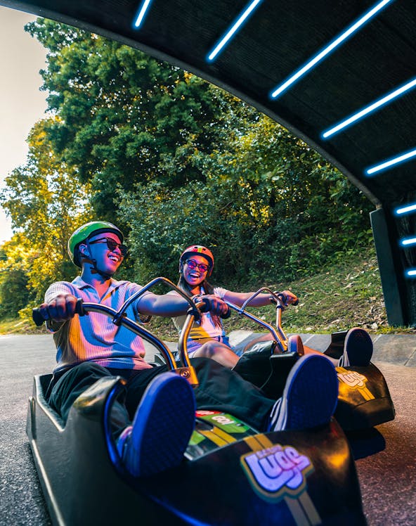 Friends riding luge carts into a tunnel on the Skyline Luge, Singapore.