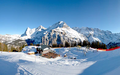 Panoramic view of Schilthorn, Murren in winter with snow-covered mountains and ski lodge.