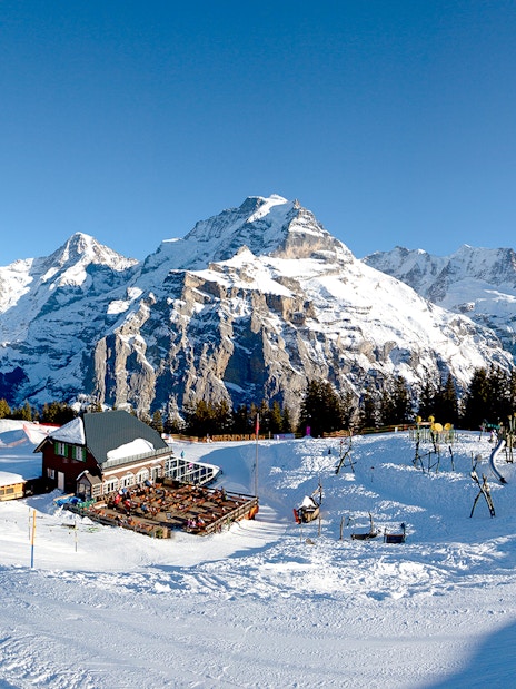 Panoramic view of Schilthorn, Murren in winter with snow-covered mountains and ski lodge.