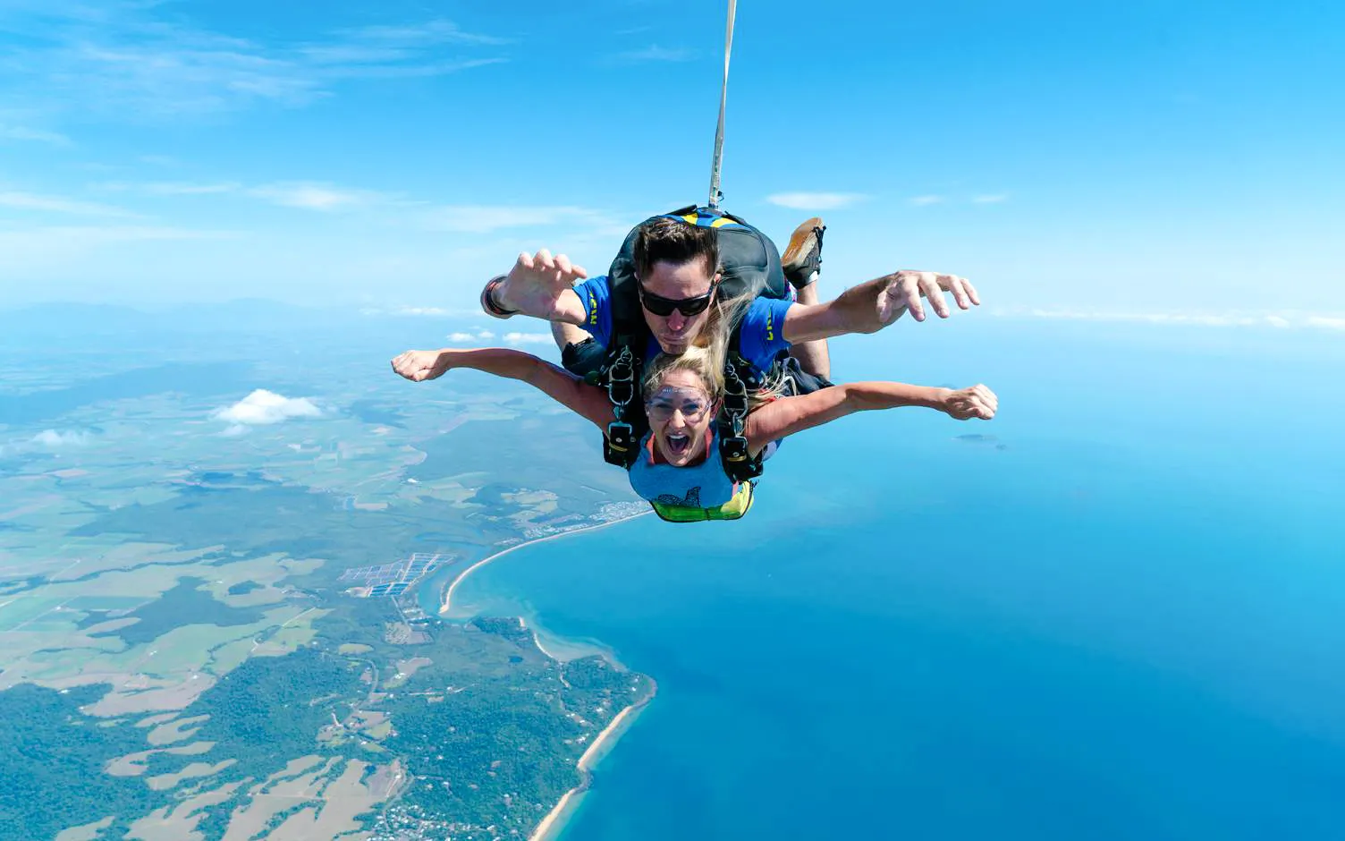 Tandem skydive over Mission Beach with ocean and coastline view.