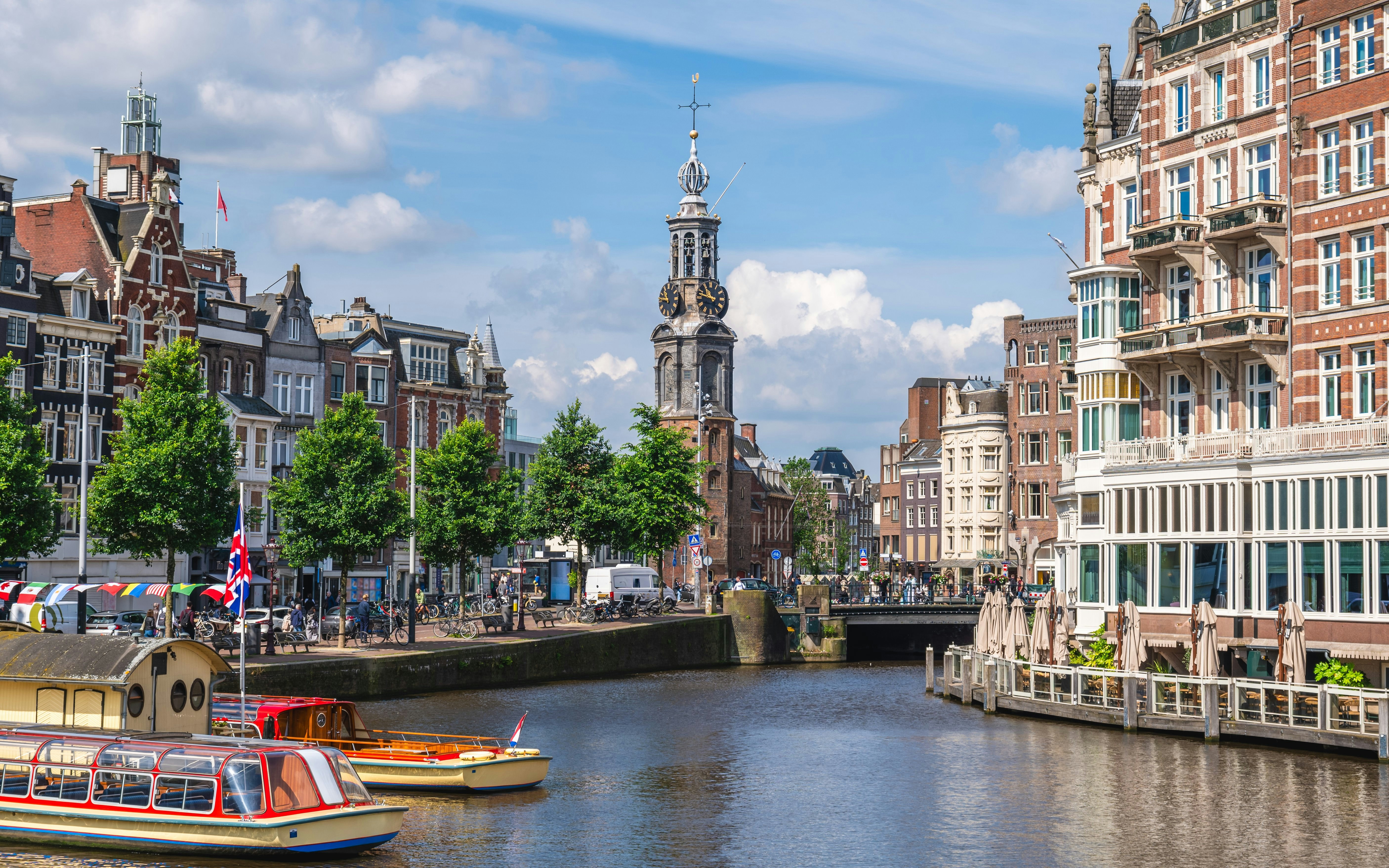 Munt Tower in Amsterdam with canal boats and historic buildings.