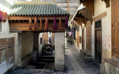 Fes Medina alley with hanging dyed yarns near Al Attarine Madrasa and tannery.