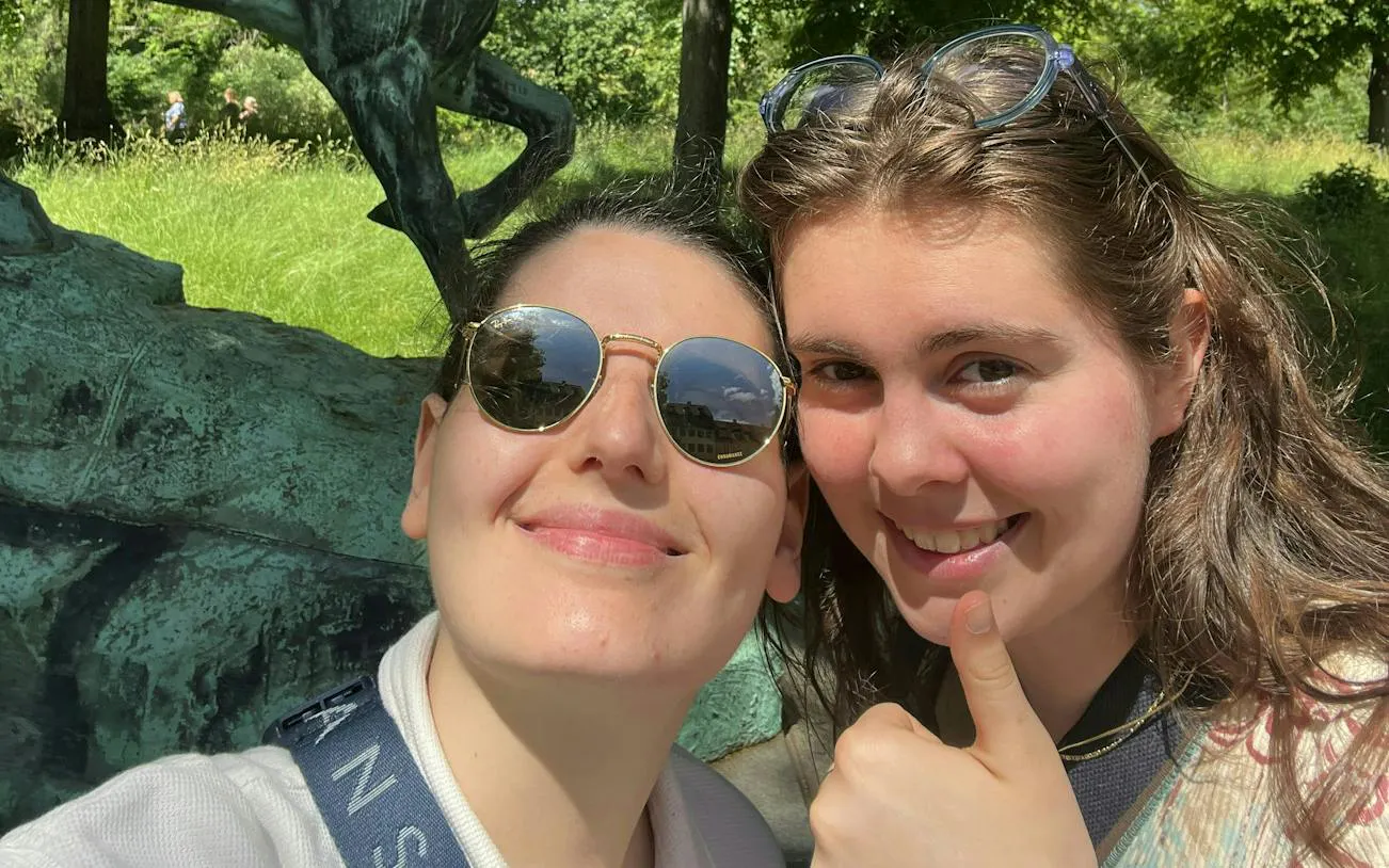 Two people smiling in front of a statue in Copenhagen's Royal District.