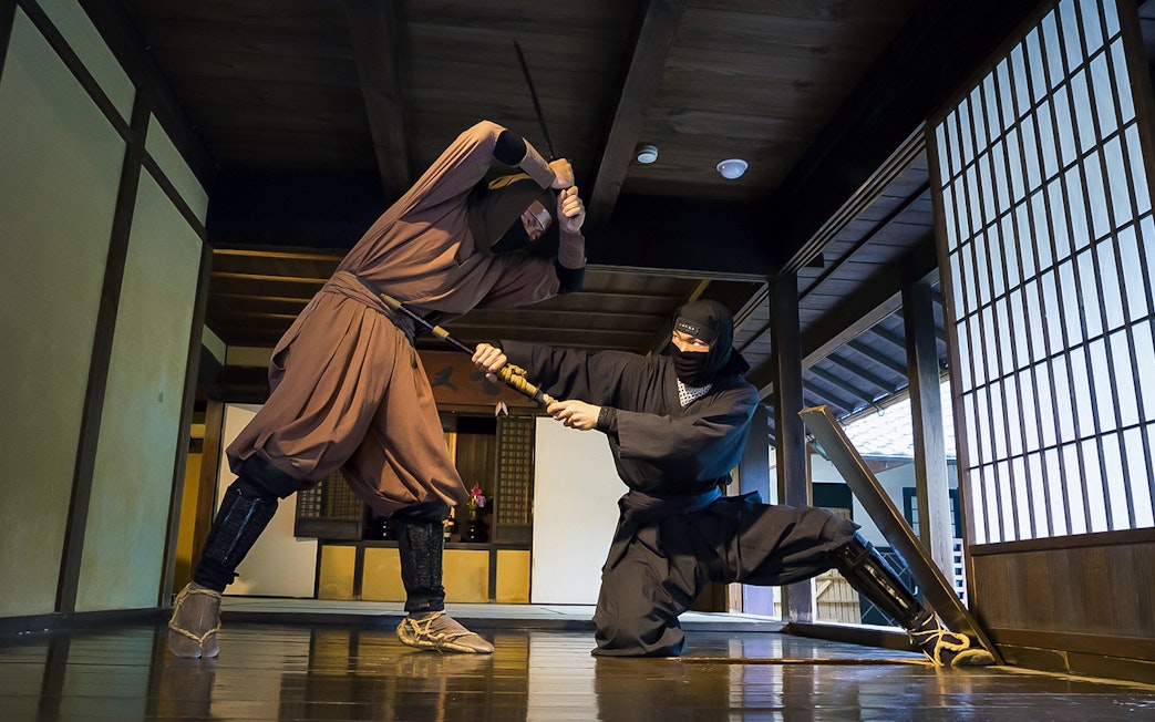 Ninjas demonstrating sword skills in a traditional Japanese dojo, Kintetsu Rail Pass.