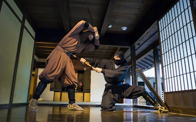 Ninjas demonstrating sword skills in a traditional Japanese dojo, Kintetsu Rail Pass.