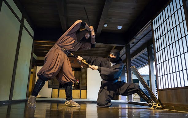 Ninjas demonstrating sword skills in a traditional Japanese dojo, Kintetsu Rail Pass.