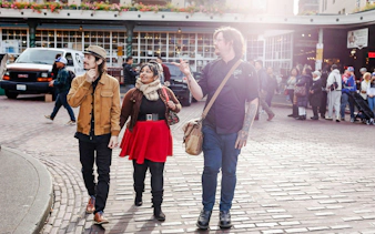 Chef guiding a food tour at Pike Place Market, Seattle, with participants exploring the area.