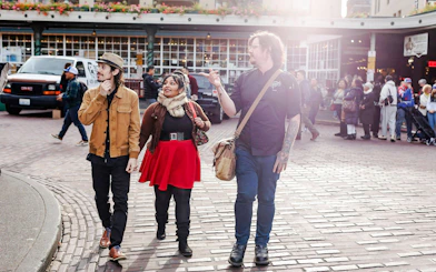 Chef guiding a food tour at Pike Place Market, Seattle, with participants exploring the area.