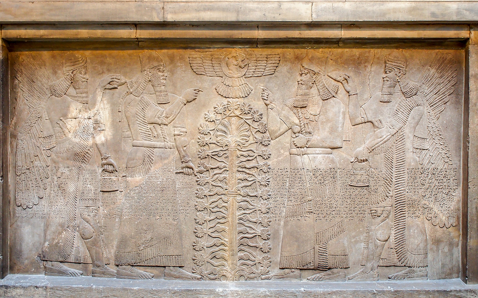 Assyrian relief sculpture at the British Museum, featuring winged figures and a sacred tree.