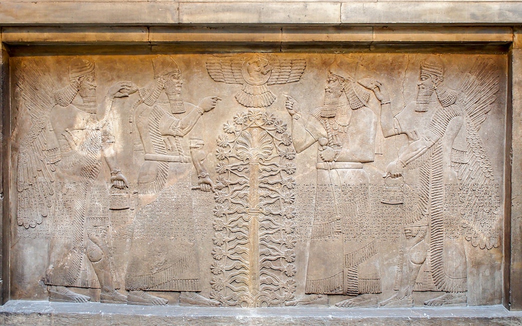 Assyrian relief sculpture at the British Museum, featuring winged figures and a sacred tree.