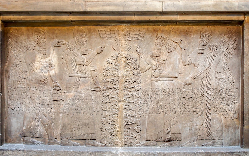 Assyrian relief sculpture at the British Museum, featuring winged figures and a sacred tree.