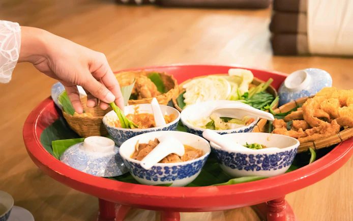 Hand picking vegetables with chili paste in a Khantoke tray, Northern Thailand.