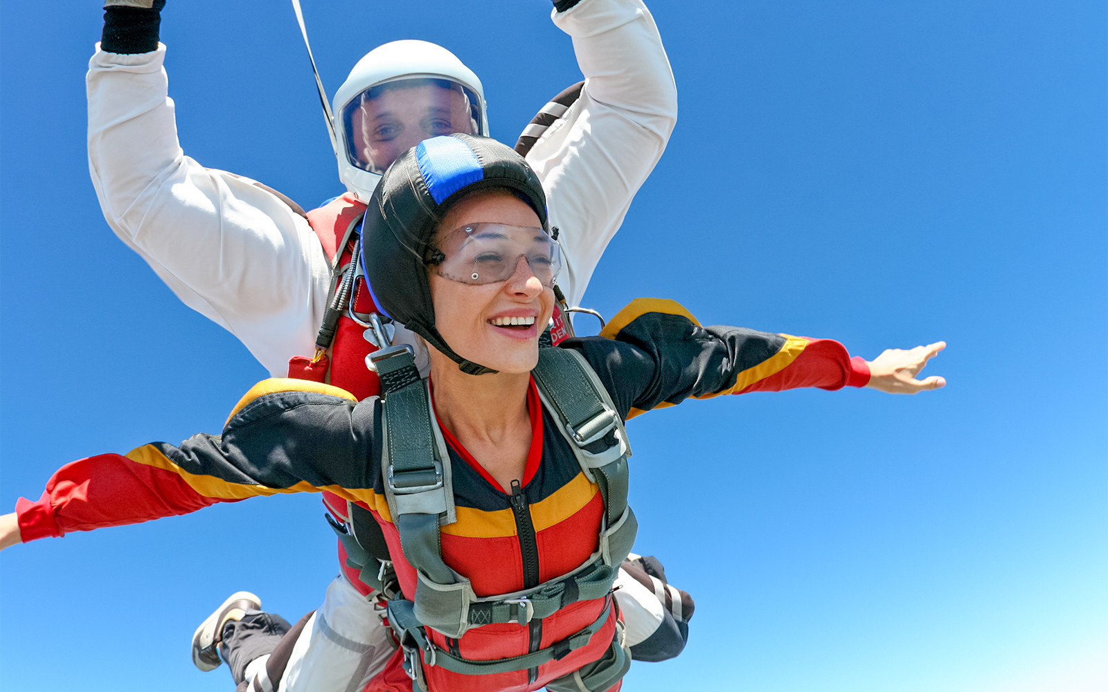 Tandem skydive over clear blue sky with instructor and participant.