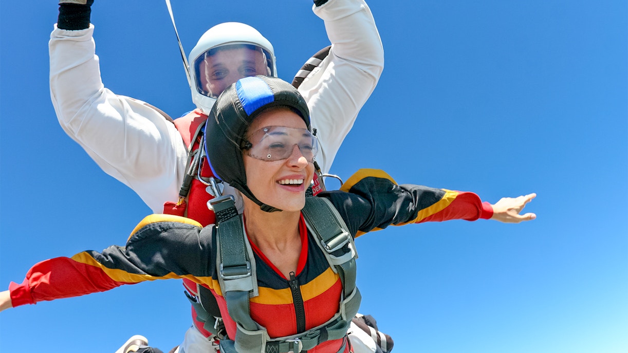 Tandem skydive over clear blue sky with instructor and participant.