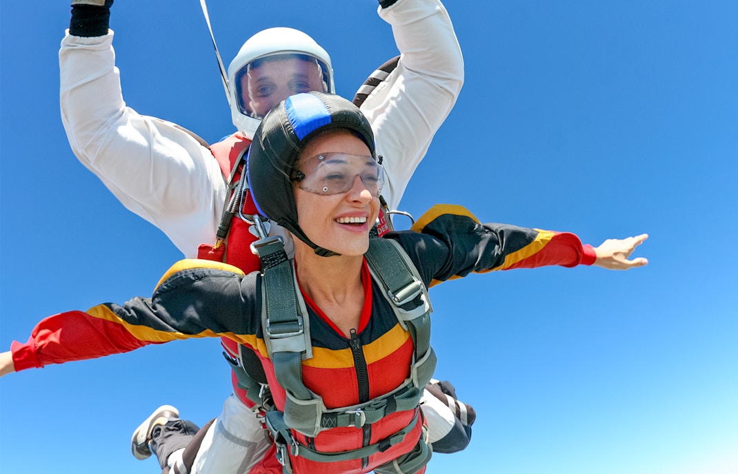 Tandem skydive over clear blue sky with instructor and participant.