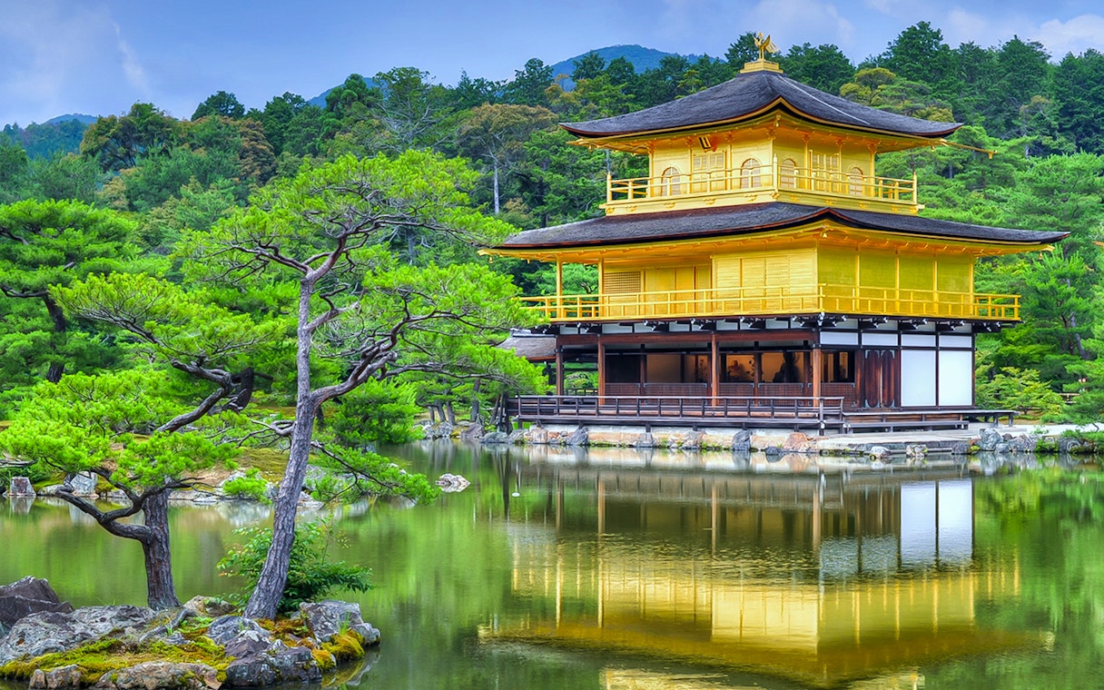 Kinkakuji golden pavilion reflecting in a serene pond surrounded by lush greenery in Kyoto.