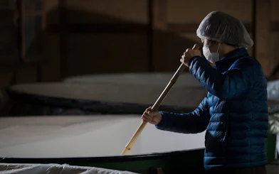 Person stirring sake mash at Takeno Sake Brewery, Kyoto.