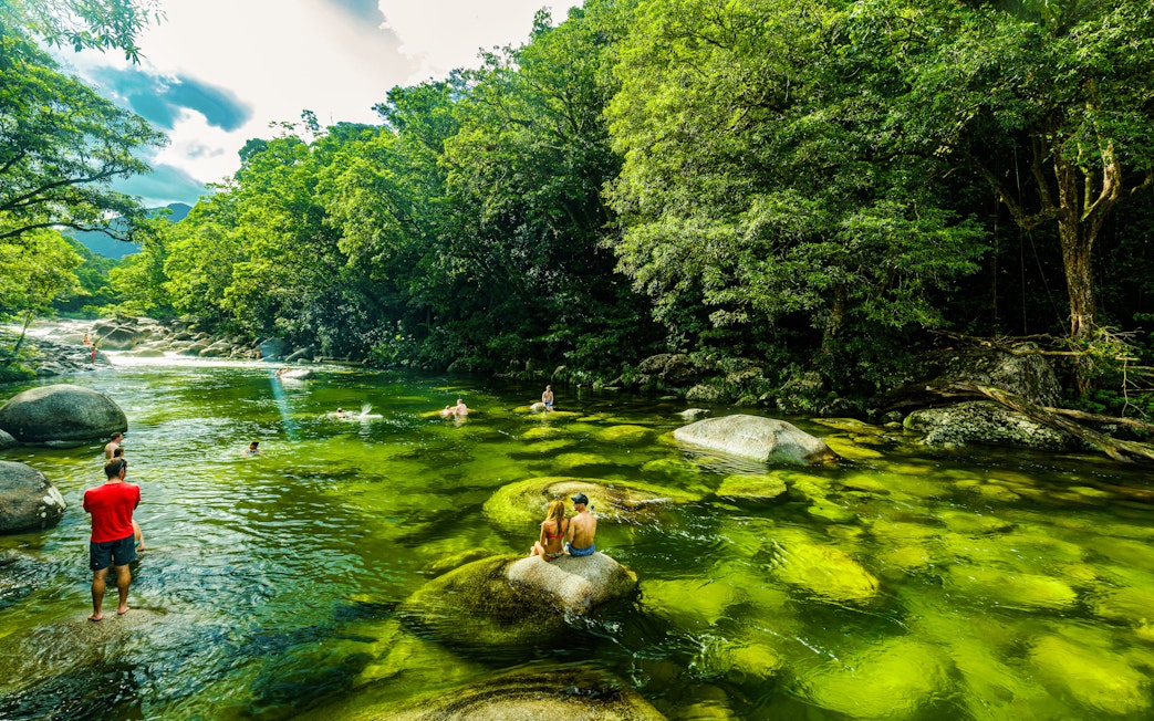 People swimming in the clear waters of Mossman Gorge surrounded by lush rainforest.
