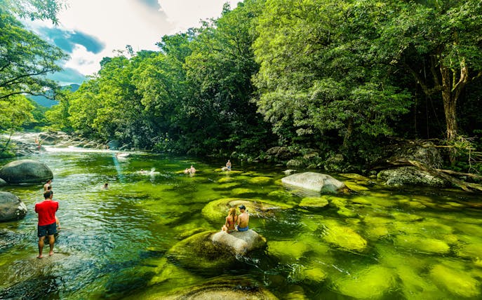 People swimming in the clear waters of Mossman Gorge surrounded by lush rainforest.