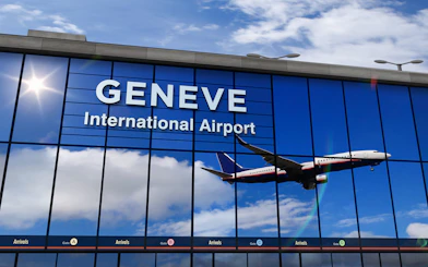 Airplane reflected in Geneva Airport terminal windows during landing.
