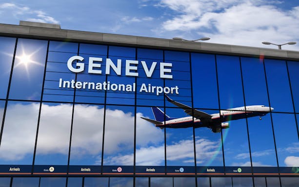 Airplane reflected in Geneva Airport terminal windows during landing.